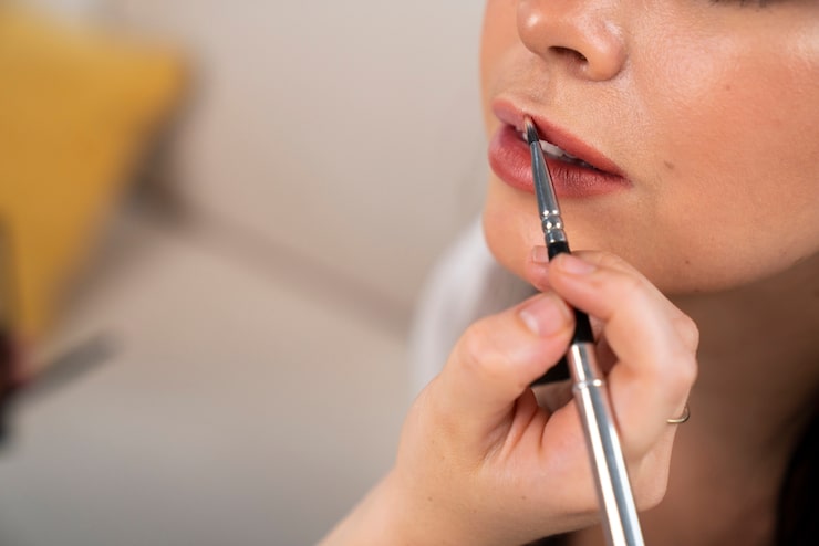 Step by step application of peach lip liner and lipstick on medium skin tone