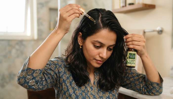 A woman carefully applying a dropper-bottle hair growth serum directly onto her scalp. A woman carefully applying a dropper-bottle hair growth serum directly onto her scalp.