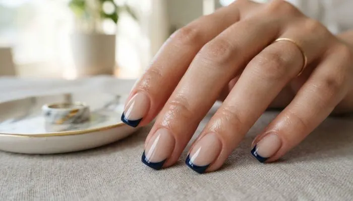 Classic French manicure with a sheer nude base and deep midnight blue tips